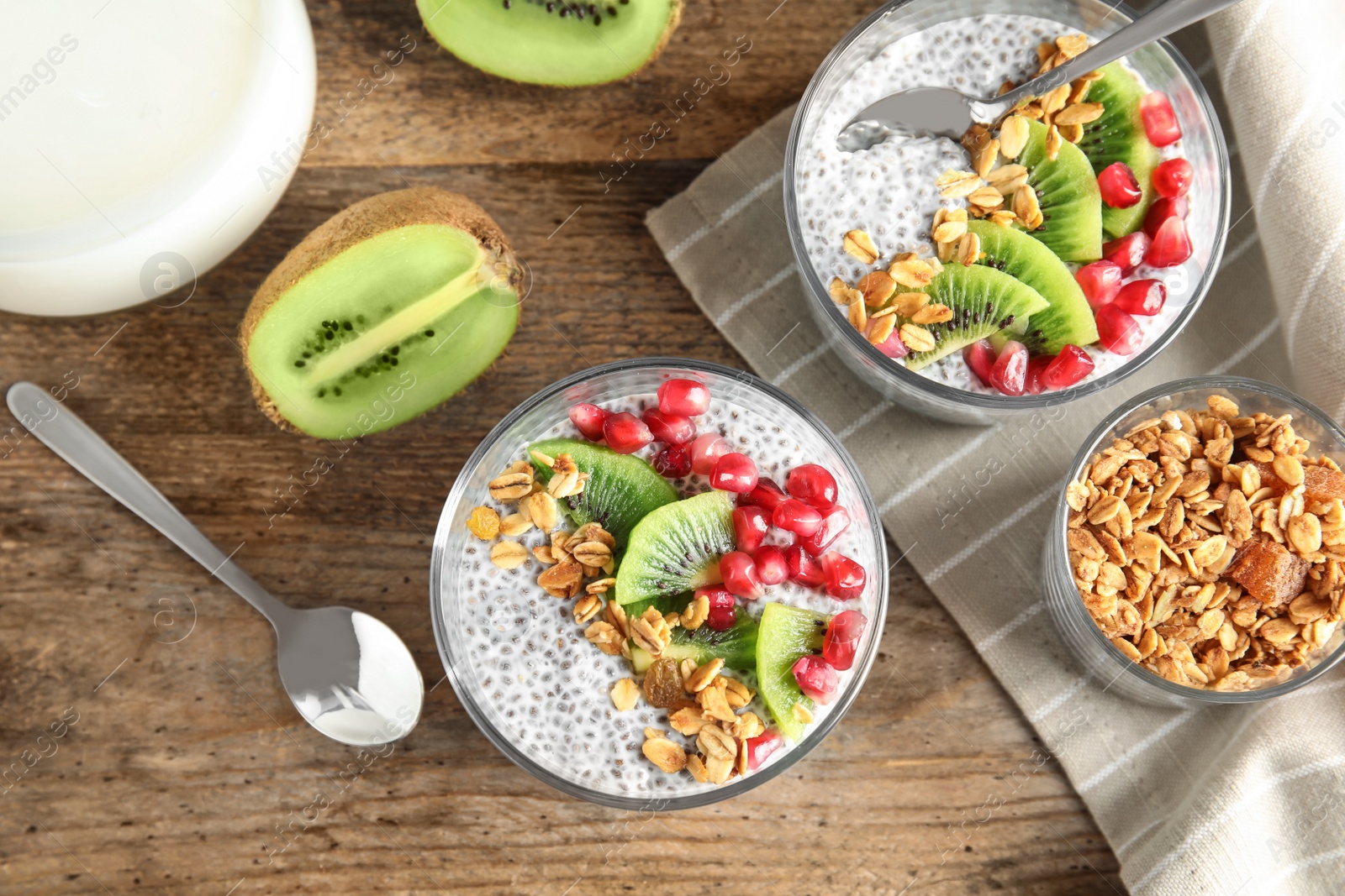 Photo of Tasty chia seed pudding with granola, kiwi and pomegranate on table, flat lay