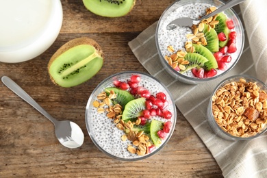 Tasty chia seed pudding with granola, kiwi and pomegranate on table, flat lay