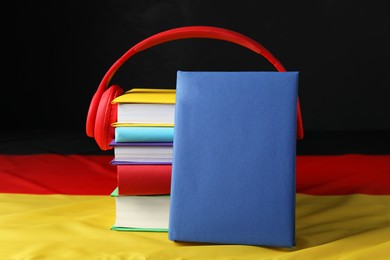Learning foreign language. Different books and headphones on flag of Germany