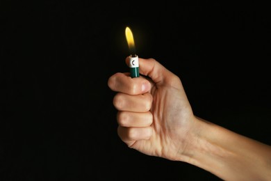 Woman holding green lighter on black background, closeup