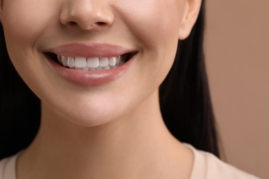 Photo of Woman with clean teeth smiling on beige background, closeup