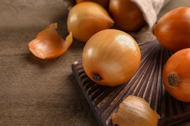 Photo of Many ripe onions on wooden table, closeup. Space for text