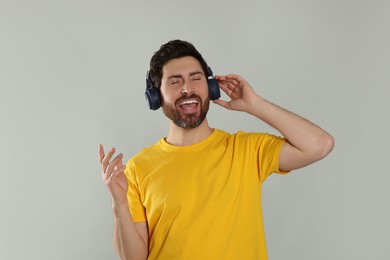 Photo of Happy man listening music with headphones on light grey background