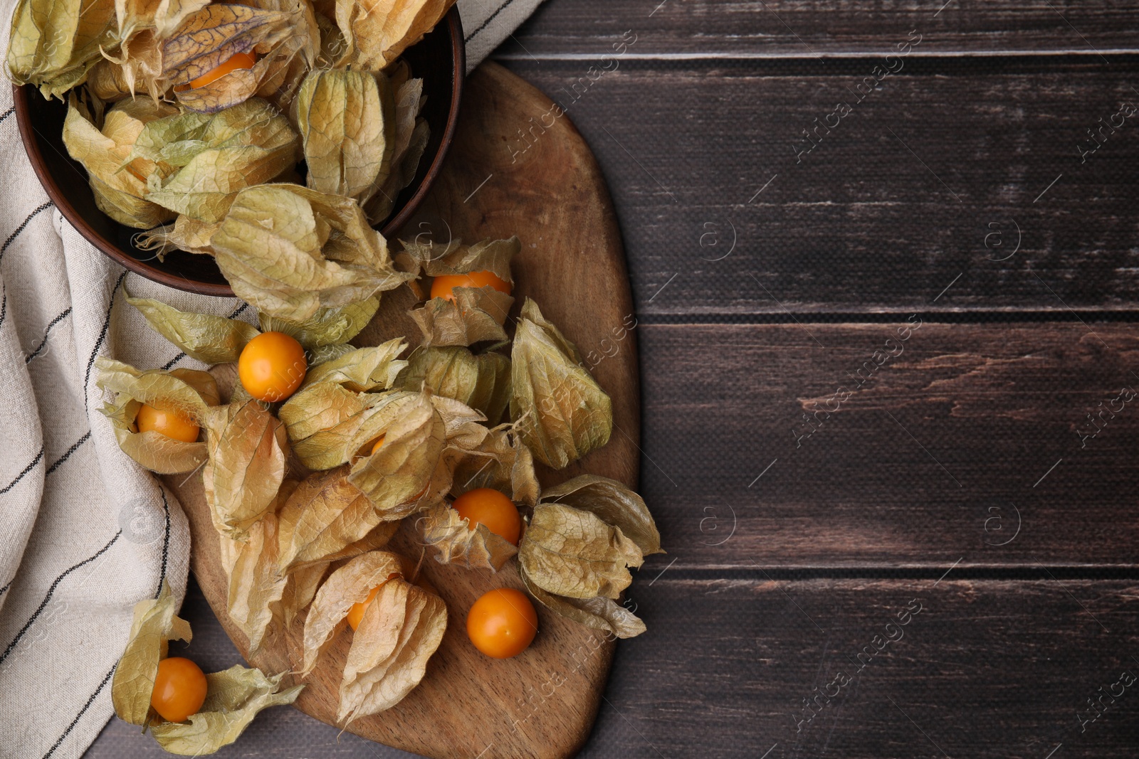 Photo of Ripe physalis fruits with calyxes on wooden table, top view. Space for text