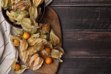 Ripe physalis fruits with calyxes on wooden table, top view. Space for text