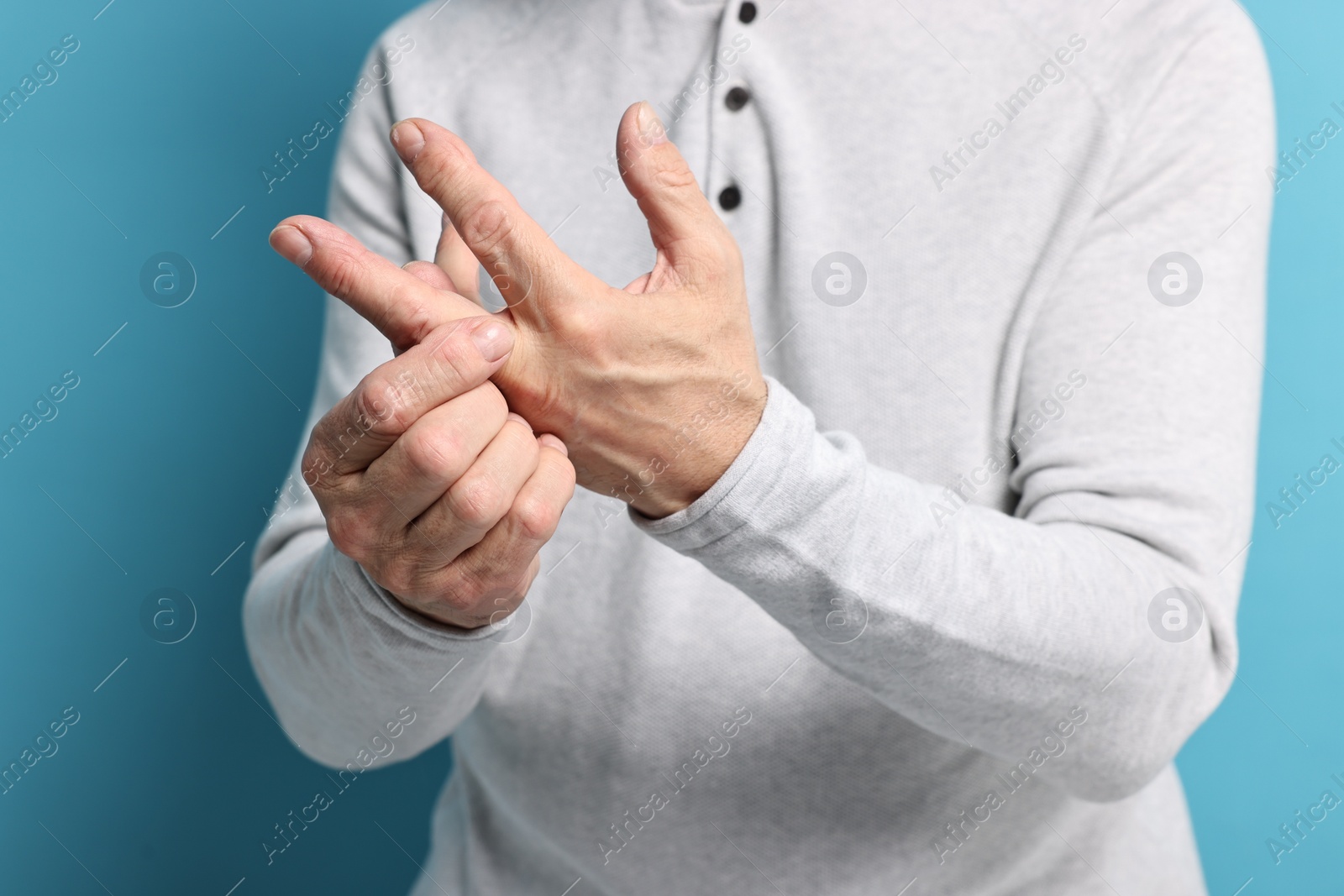 Photo of Arthritis symptoms. Man suffering from pain in hand on light blue background, closeup