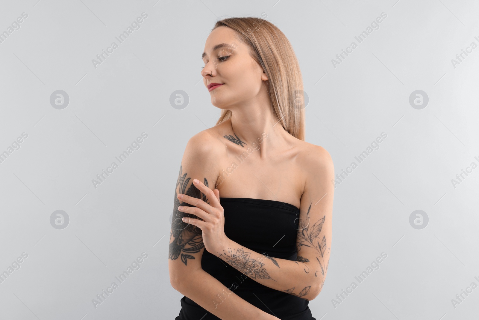 Photo of Portrait of beautiful tattooed woman on light background