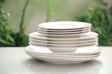 Stack of clean dishes on grey table against blurred background