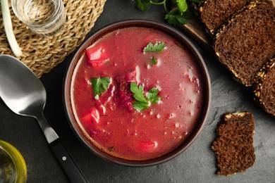 Stylish brown clay bowl with Ukrainian borsch on black table, flat lay