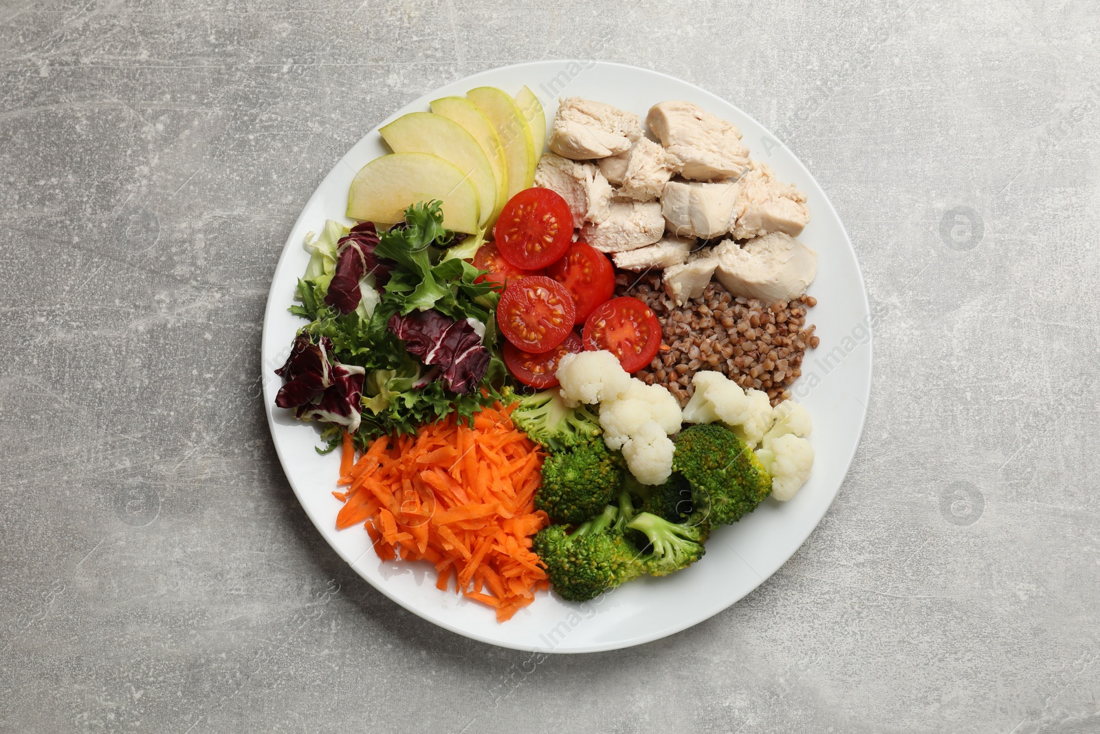 Photo of Balanced diet and healthy foods. Plate with different delicious products on grey table, top view