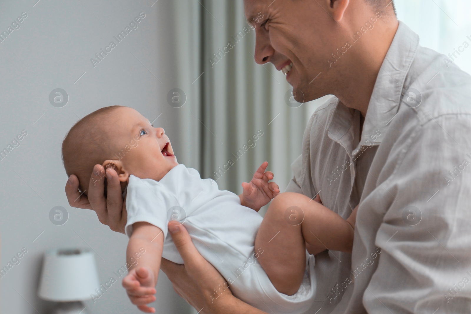 Photo of Happy father holding his cute baby at home