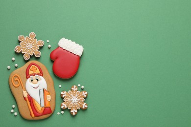 Photo of Tasty gingerbread cookies on green background, flat lay with space for text. St. Nicholas Day celebration