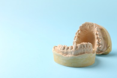 Photo of Dental model with gums on light blue background, space for text. Cast of teeth