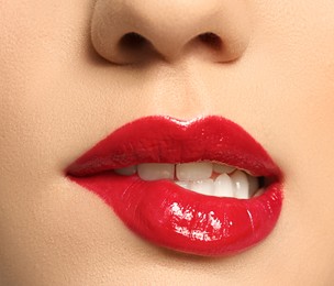 Photo of Beautiful young woman with bright makeup biting lip on white background, closeup