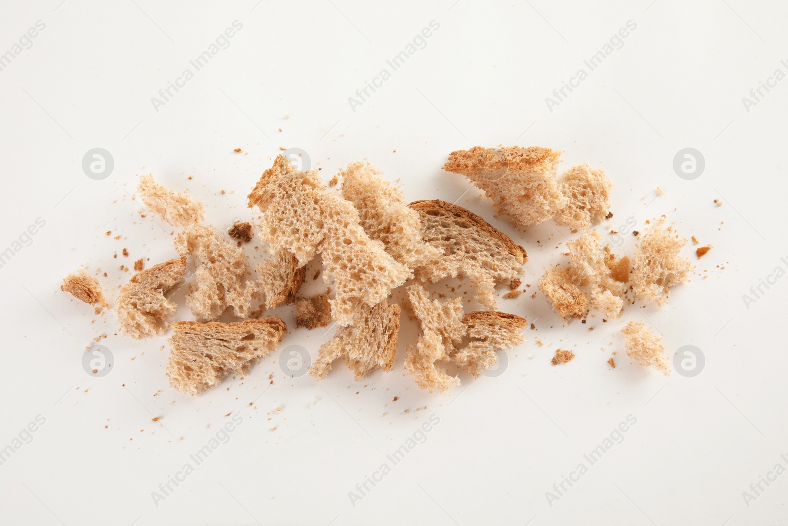 Photo of Scattered bread crumbs on white background, top view