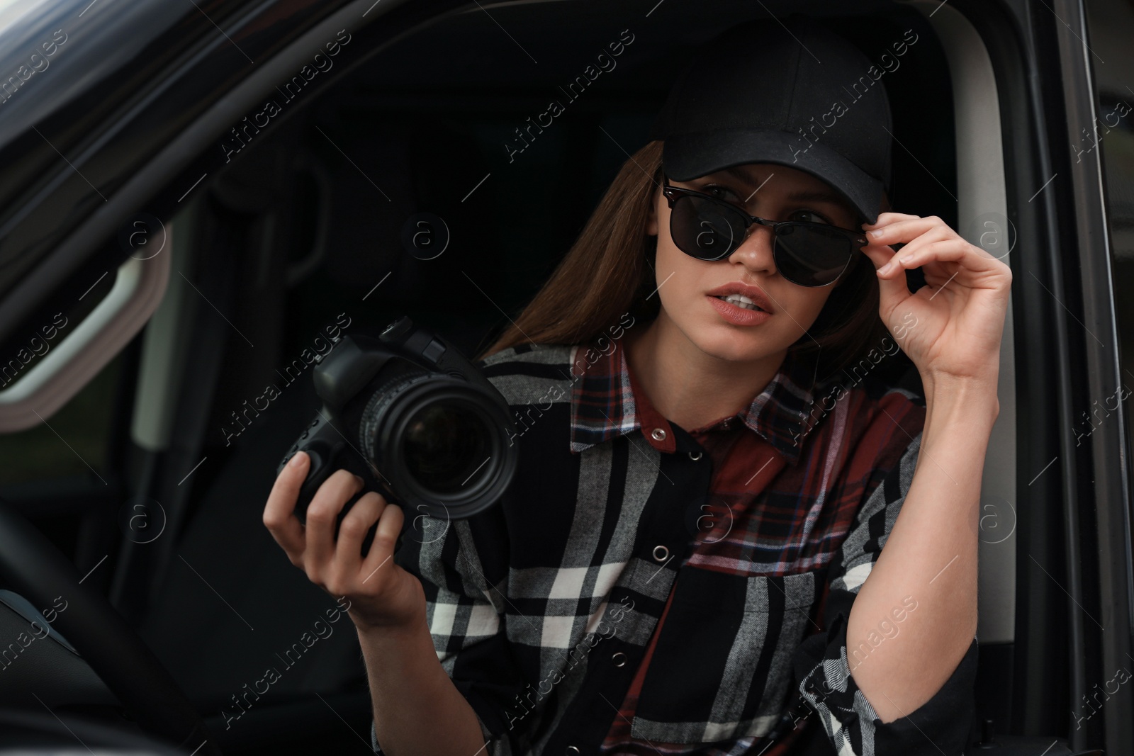 Photo of Private detective with camera spying from car