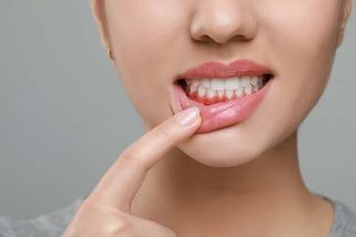 Image of Woman showing inflamed gum on grey background, closeup