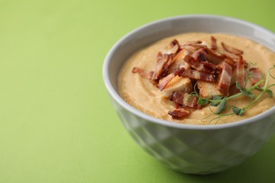 Photo of Delicious lentil soup with bacon and croutons on green background, closeup. Space for text