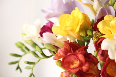 Photo of Beautiful bouquet of spring freesia flowers on light background, closeup