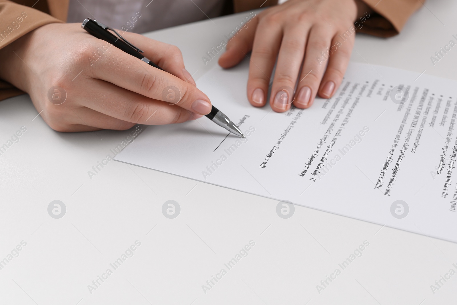 Photo of Businesswoman signing contract at white table, closeup of hands