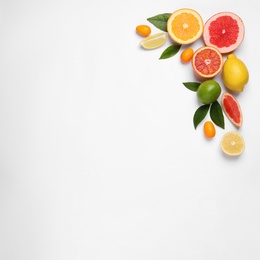 Photo of Fresh juicy citrus fruits with green leaves on light background, flat lay. Space for text