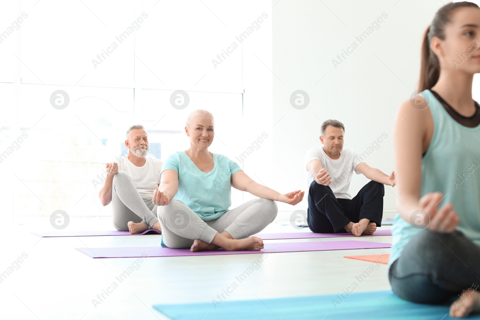 Photo of Group of people in sportswear practicing yoga indoors