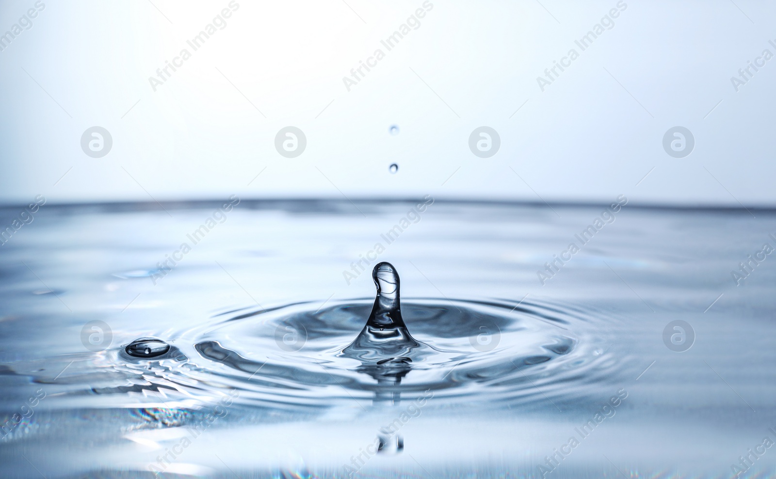 Photo of Splash of clear water with drop on light background, closeup