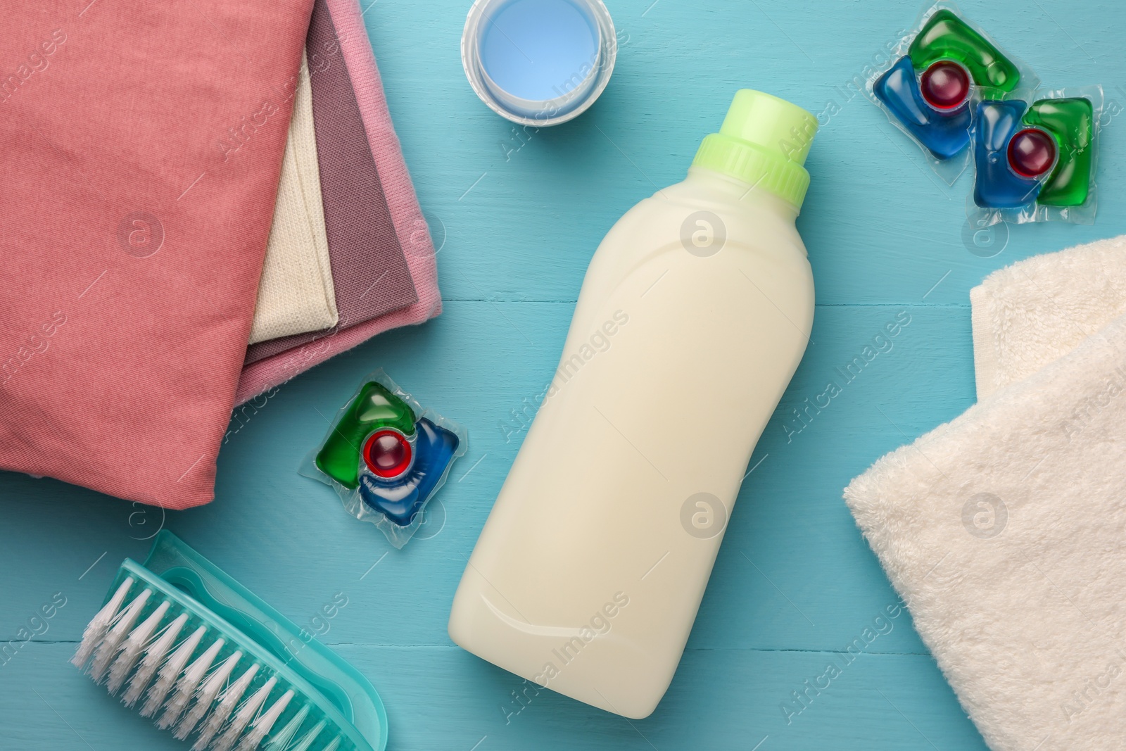 Flat lay composition with bottle of fabric softener on light blue wooden table Photo of Flat lay composition with bottle of fabric softener on light blue wooden table