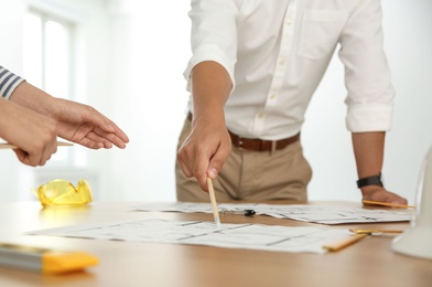 People working with construction drawings at table, closeup