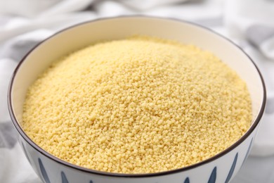 Photo of Raw couscous in bowl on table, closeup