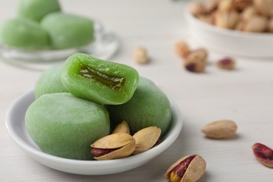 Photo of Delicious mochi and pistachios on white wooden table, closeup with space for text. Traditional Japanese dessert