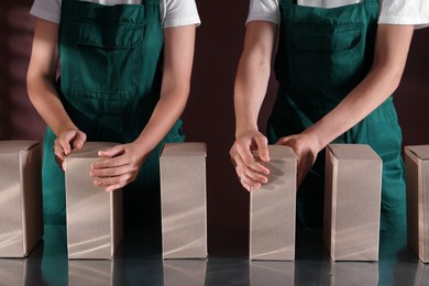 Photo of People packing cardboard boxes at production line, closeup