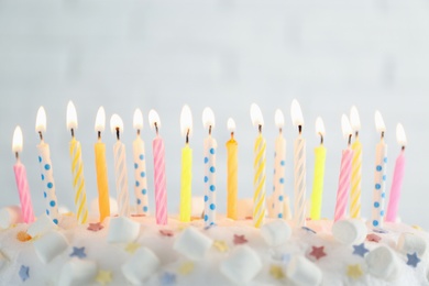 Photo of Birthday cake with burning candles on light grey background, closeup