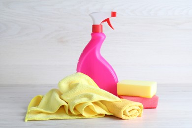 Photo of Microfiber cloths, sponges and detergent on white wooden table