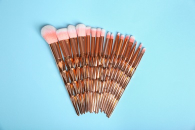 Photo of Flat lay composition with set of professional makeup brushes on light blue background