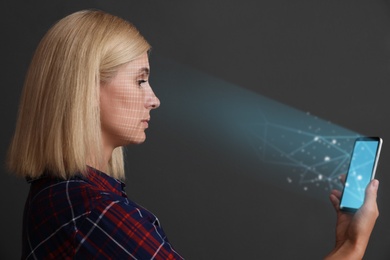 Image of Woman using facial detection system of modern smartphone on grey background
