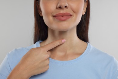 Photo of Endocrine system. Woman doing thyroid self examination on light grey background, closeup