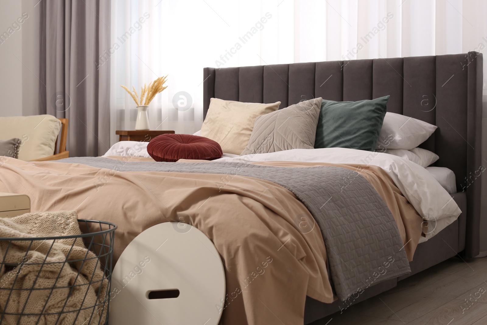 Photo of Large comfortable bed with soft pillows and duvet in room. Home textile