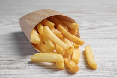 Delicious french fries in paper box on white wooden table, closeup