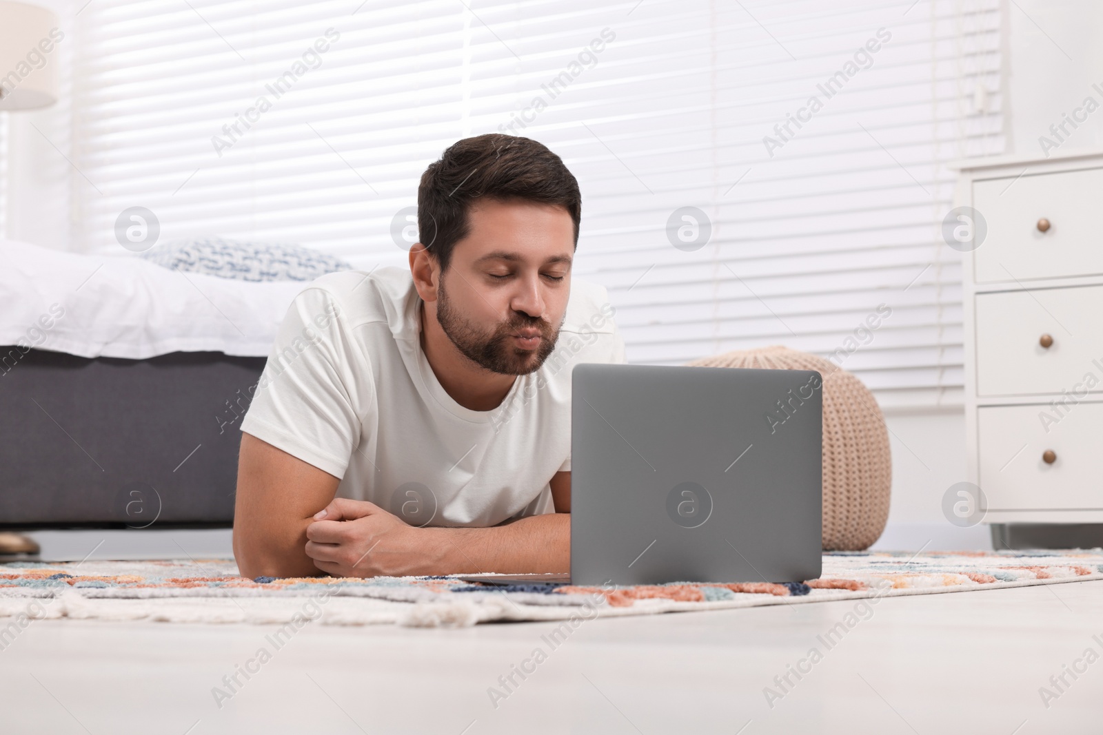 Photo of Man sending air kiss during video chat via laptop at home. Long-distance relationship