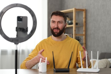 Photo of Smiling technology blogger recording video review about WI-FI devices at home