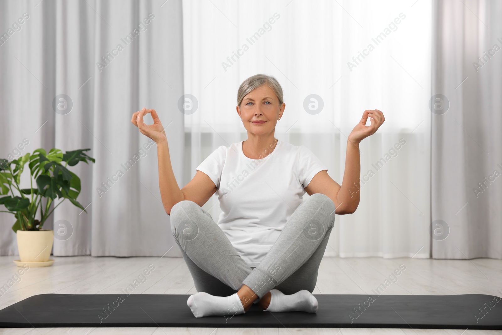 Photo of Senior woman practicing yoga on mat at home