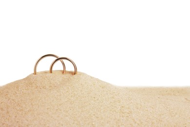 Honeymoon concept. Two golden rings and sand isolated on white