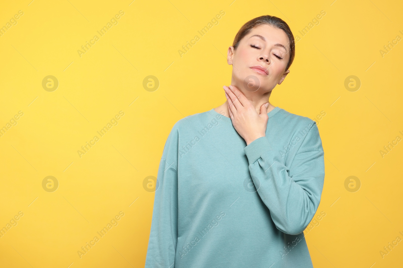 Photo of Woman suffering from sore throat on orange background. Space for text