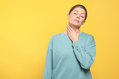 Photo of Woman suffering from sore throat on orange background. Space for text