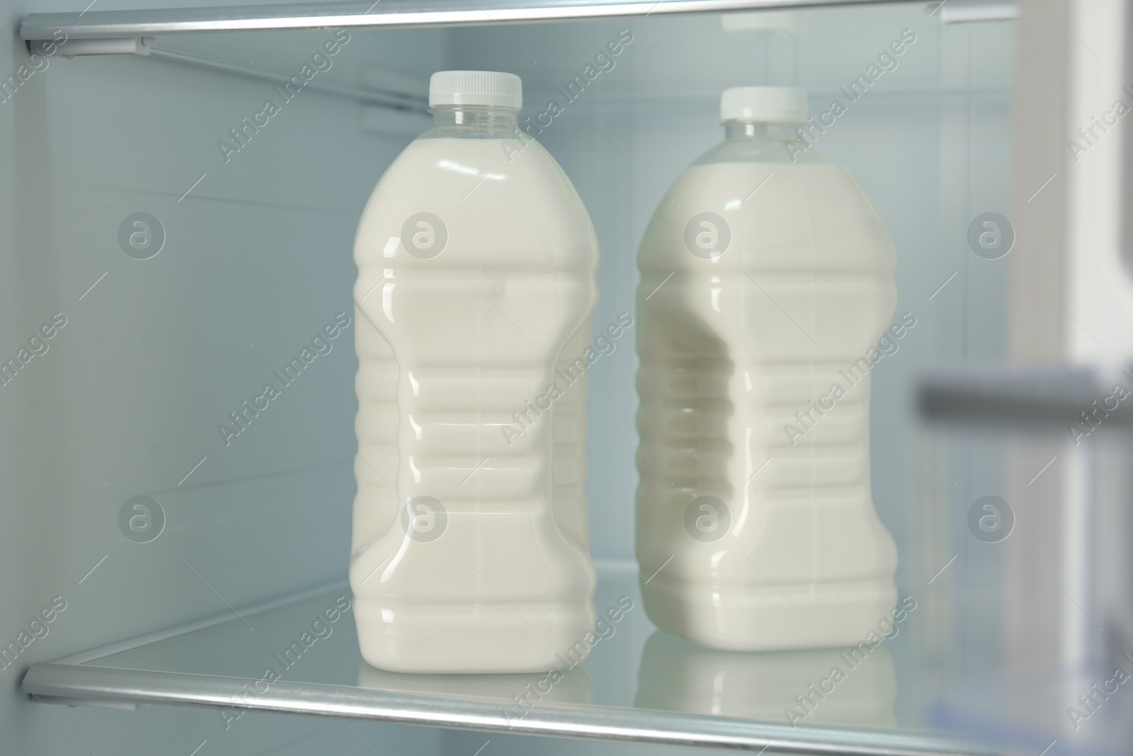 Photo of Gallons of fresh milk in refrigerator, closeup