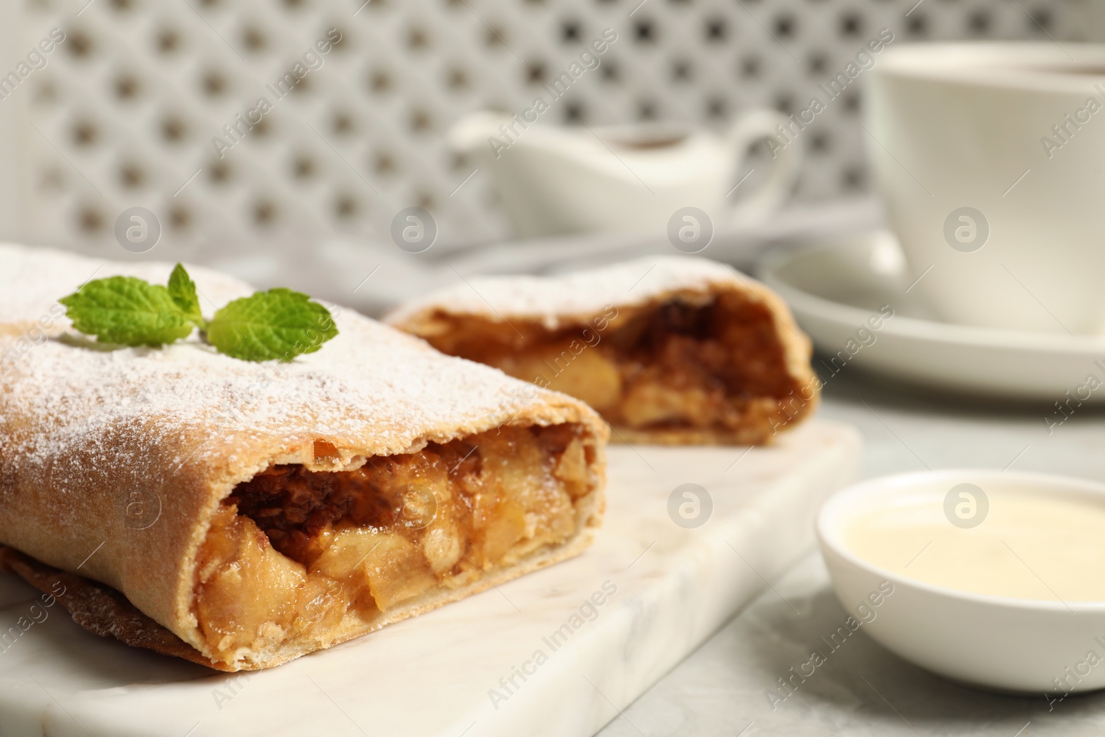 Photo of Delicious strudel with apples, nuts and powdered sugar on table, closeup. Space for text