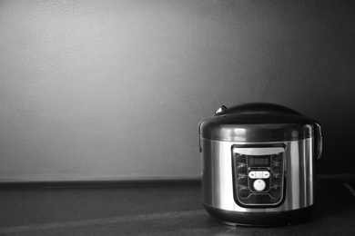 Photo of Modern multi cooker on table near black wall, space for text