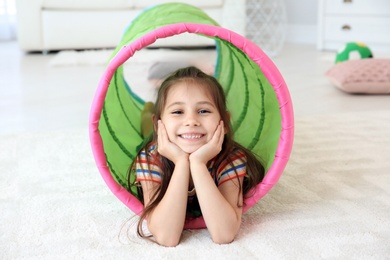 Photo of Cute little child in playing tunnel on floor, indoors