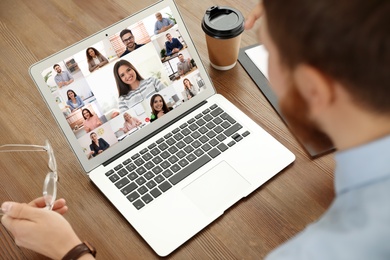 Man having video chat with team at table, closeup